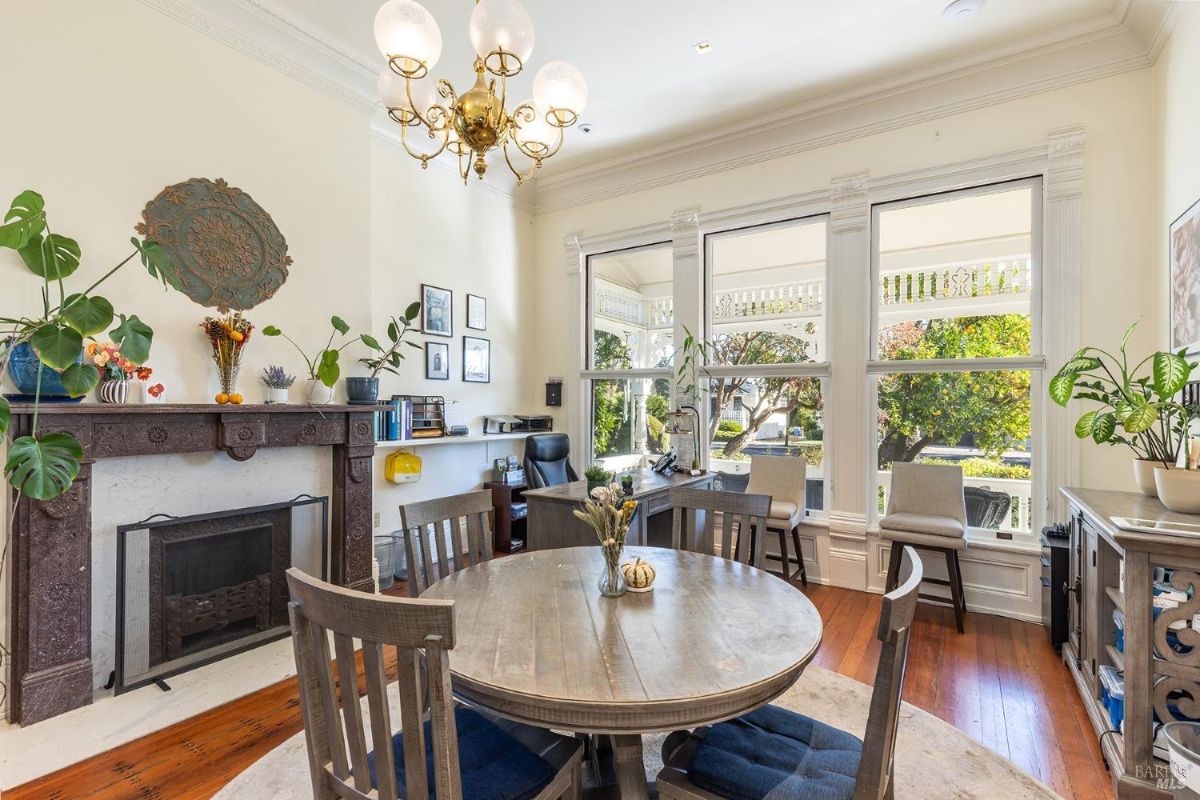 Another angle of the office showcases more of the seating arrangement, windows with a scenic view outside, and a sophisticated chandelier. The decor blends functionality with aesthetic appeal.