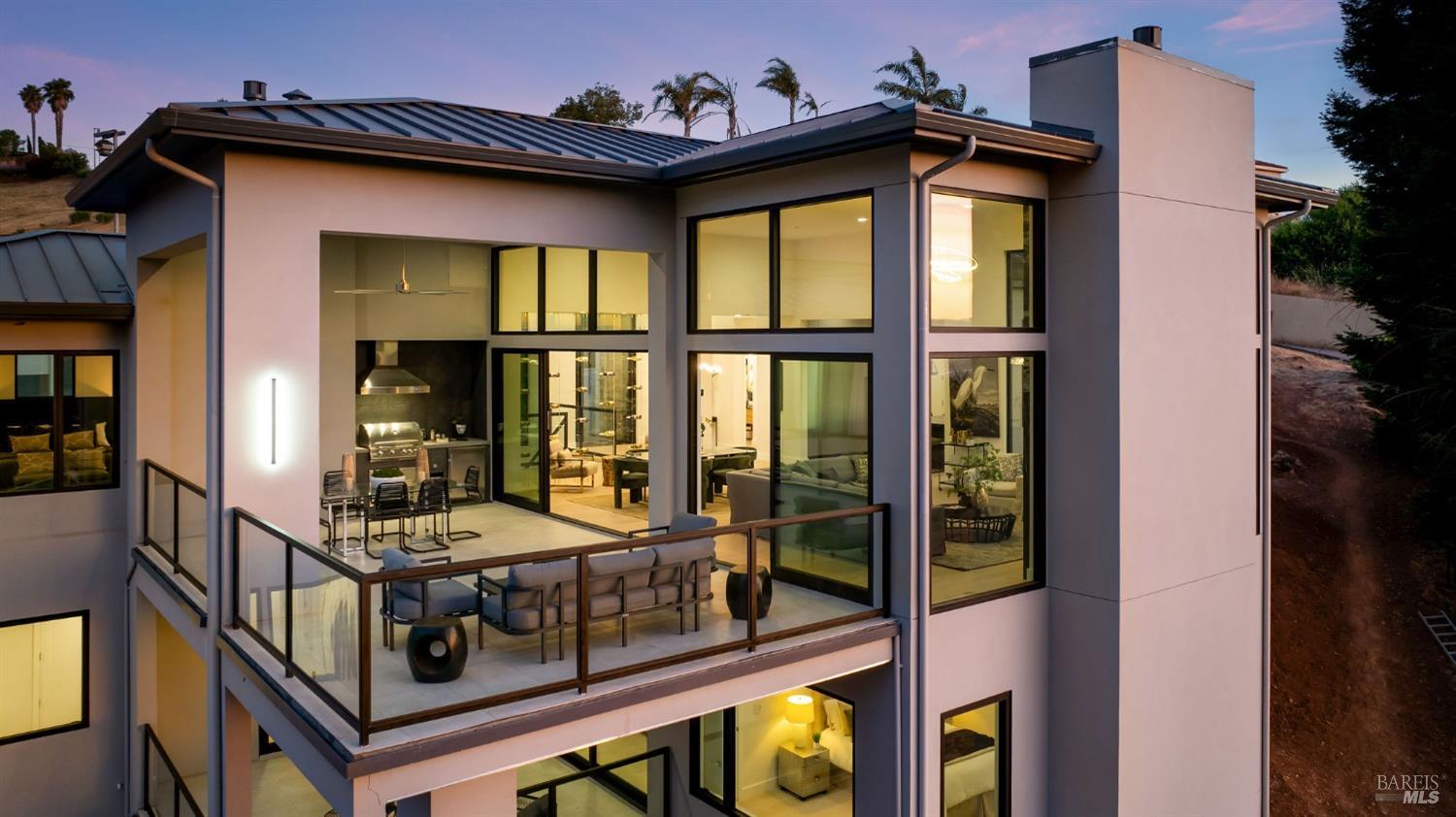 An exterior view of a modern house featuring large glass walls and multiple balconies.