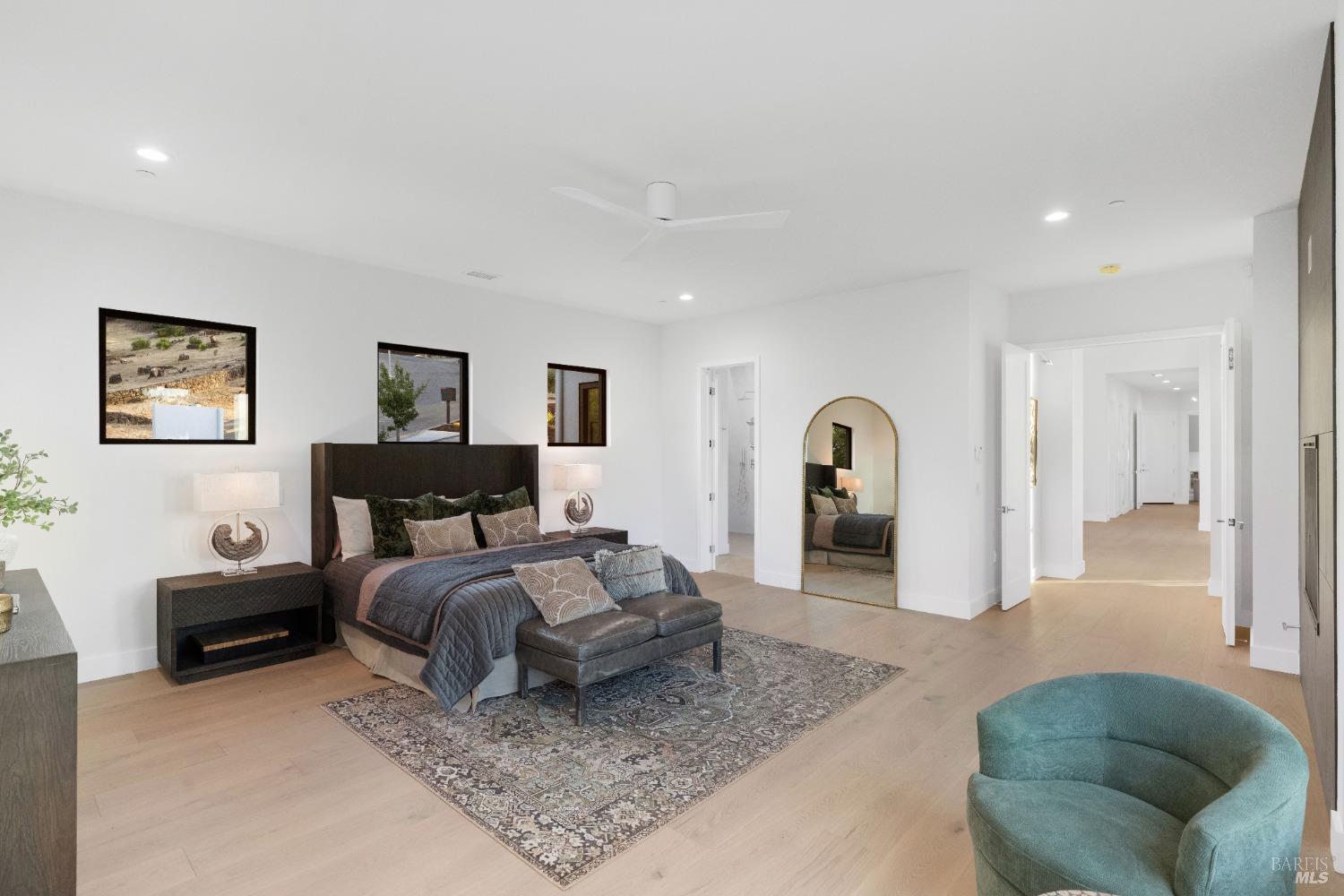 Spacious primary bedroom with a dark bedframe, sitting area, and a large area rug.