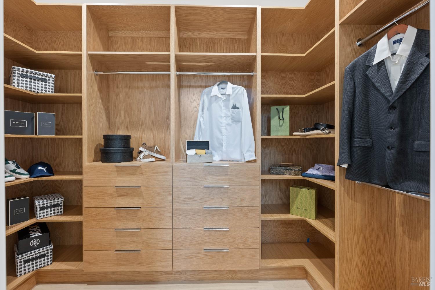 Walk-in closet with wooden shelving, drawers, and clothing neatly displayed.