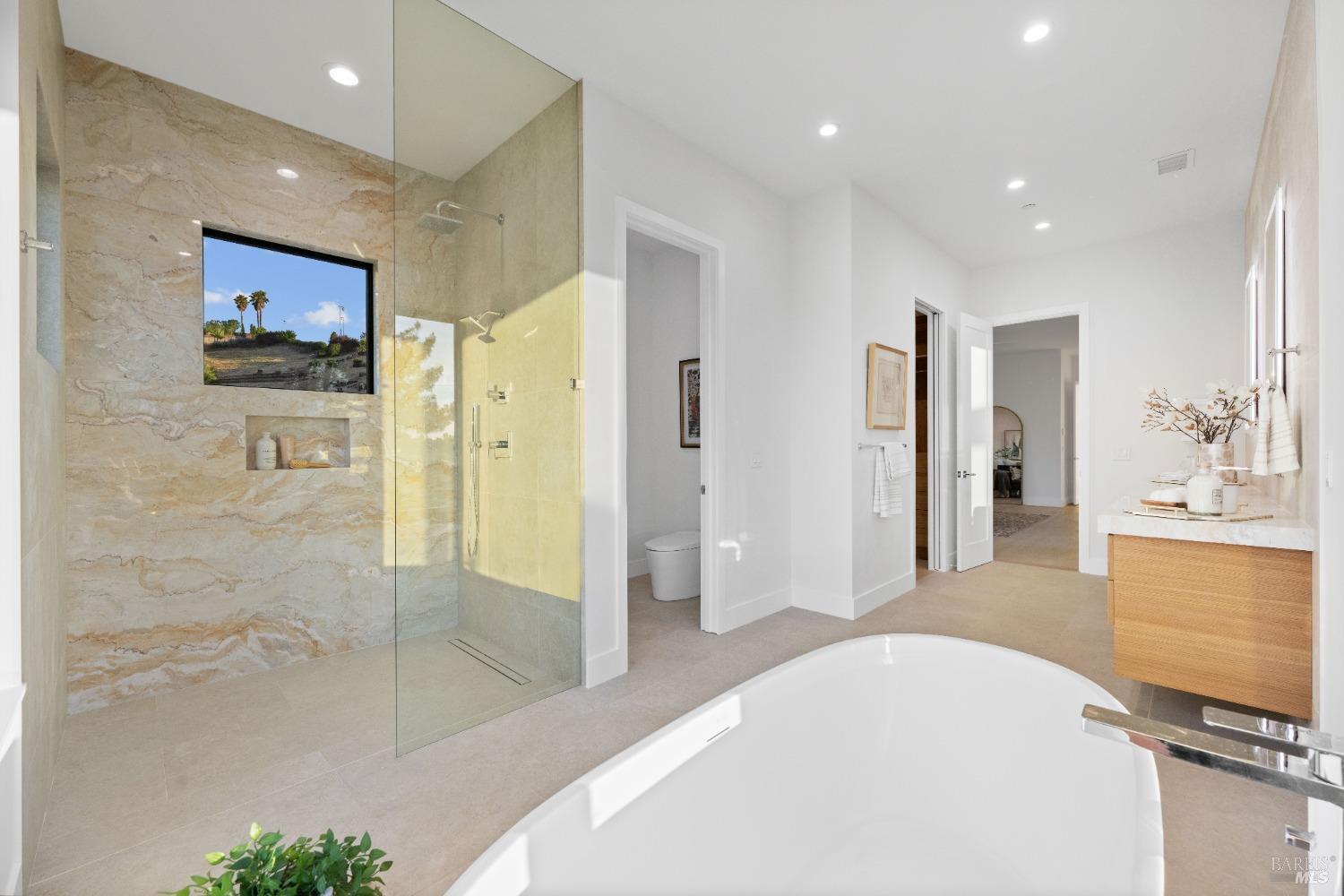 Bathroom featuring a walk-in shower with beige stone tile and a freestanding tub.