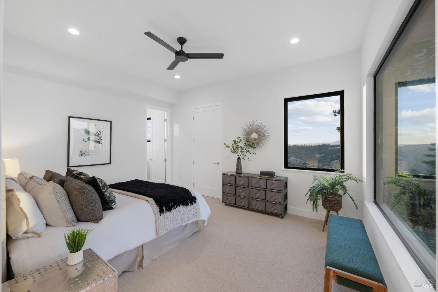 Bedroom with a neatly made bed, decorative pillows, and windows providing a scenic view.