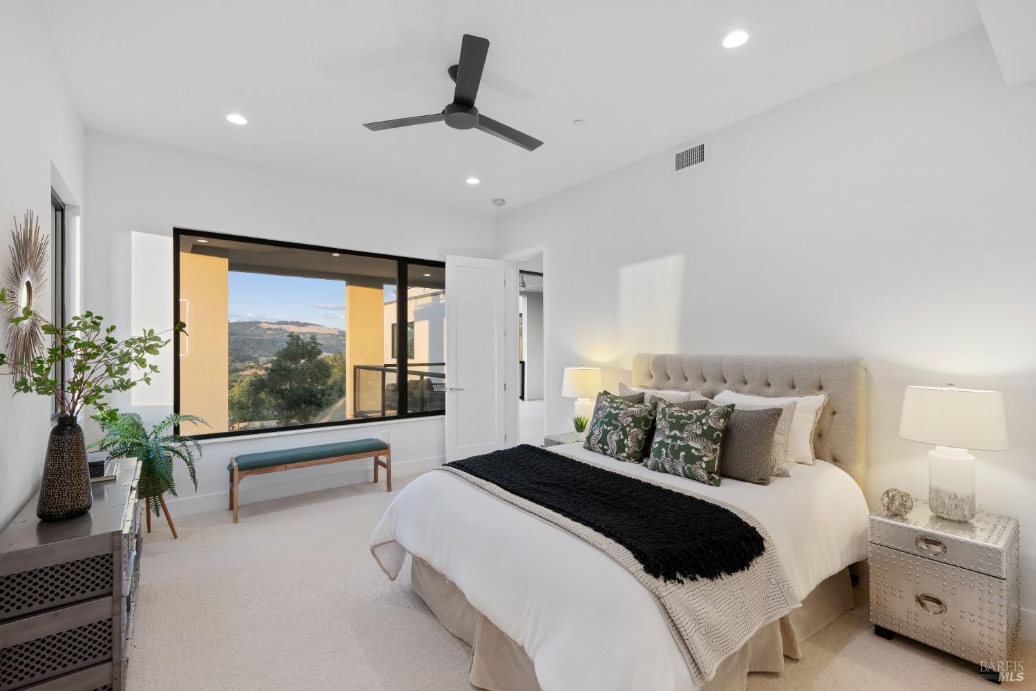 Cozy bedroom featuring a tufted headboard, black accent throw, and access to a balcony.