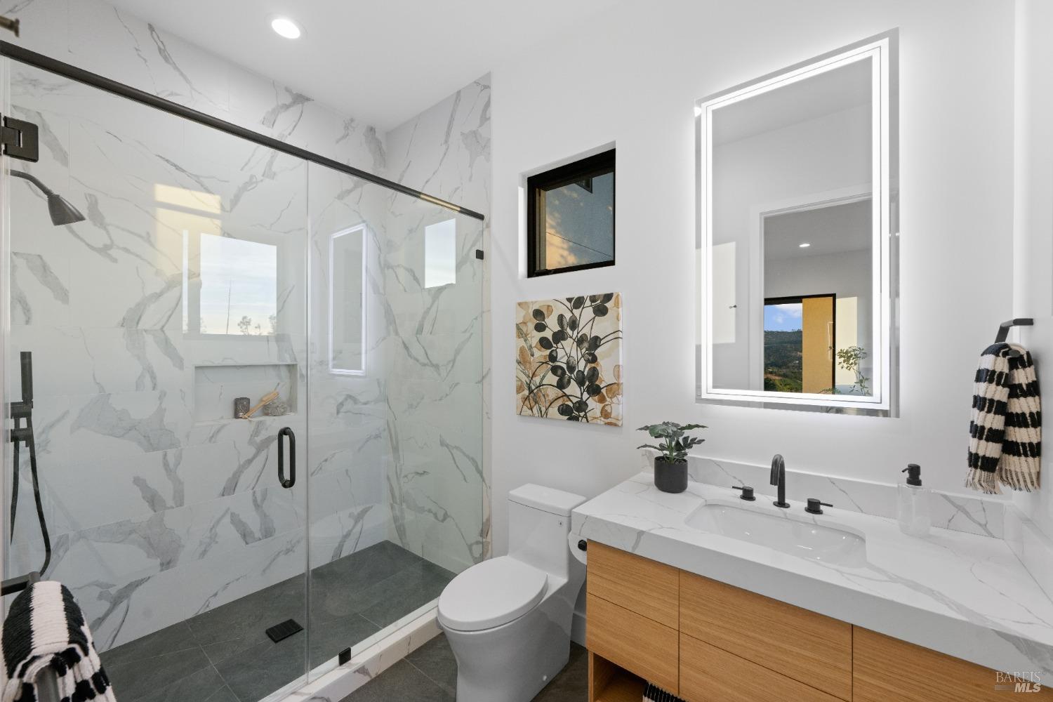 Bathroom with white marble tile, glass shower enclosure, and single vanity.