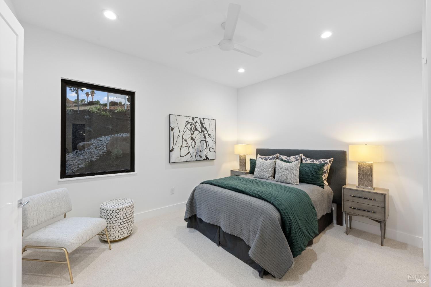 Bedroom includes a dark green bedspread, modern furniture, and a window with a garden view.