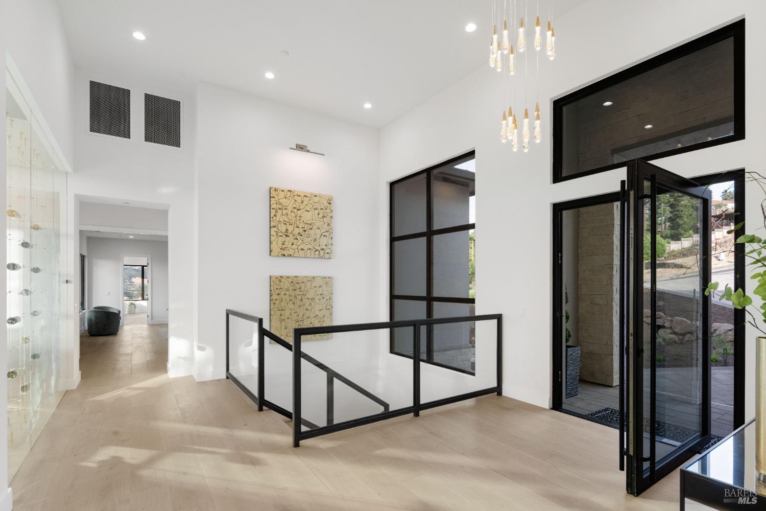 A spacious entryway with a glass door, modern light fixtures, and wall art.