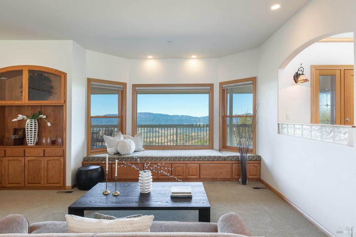 Living room features a built-in wooden bench with storage, framed by large windows overlooking a scenic view.