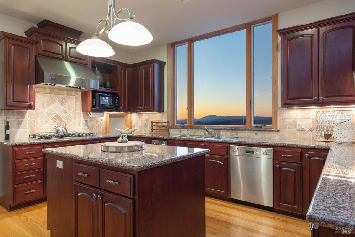 Kitchen includes granite countertops, stainless steel appliances, and a window showcasing a sunset view.