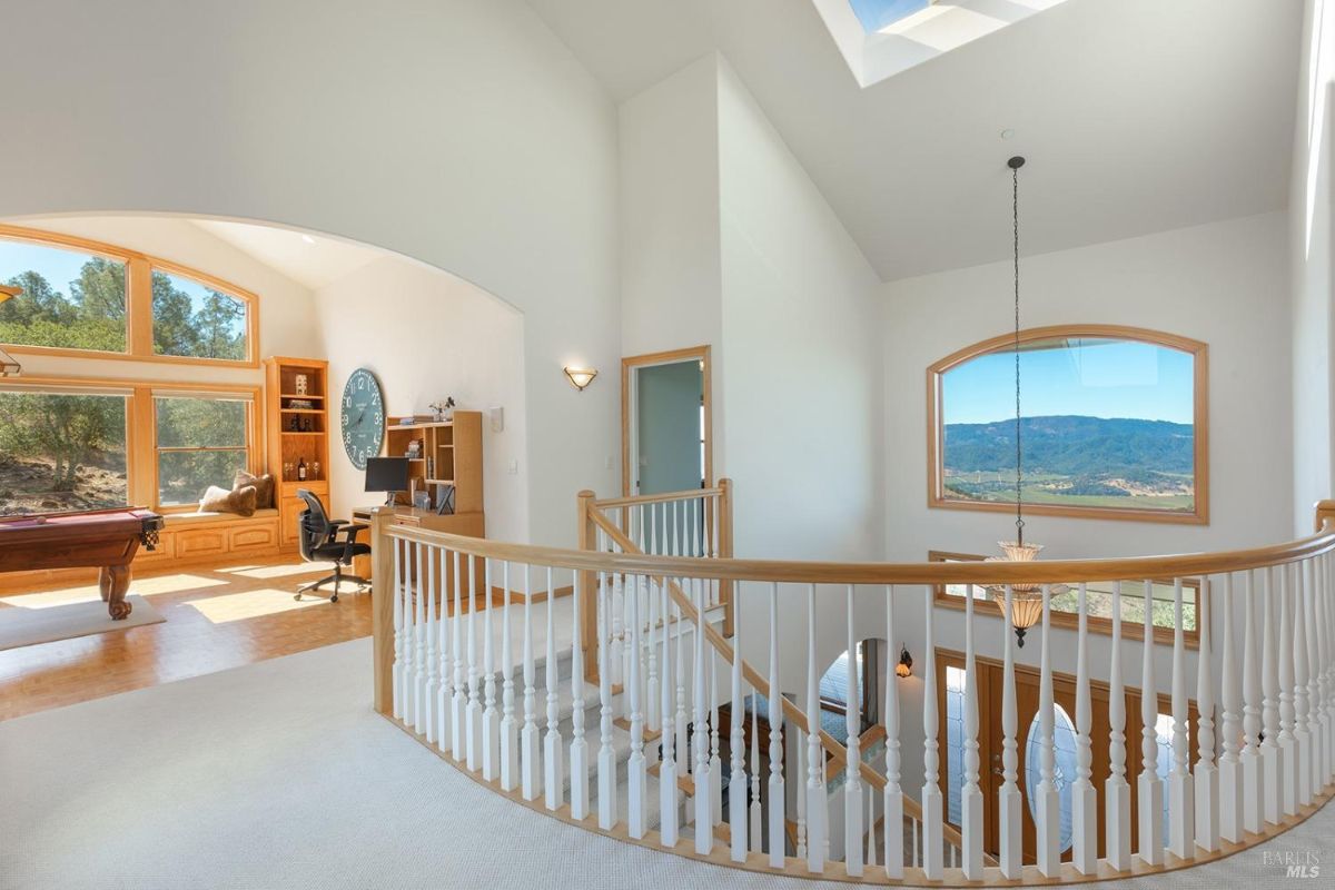 Open staircase leading to a bright loft area with a desk and large windows.