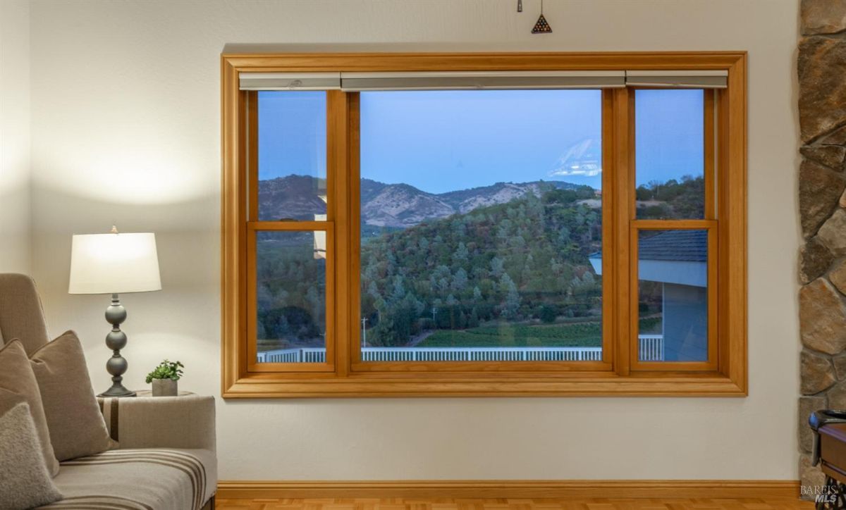 Window offering a view of a hilly landscape framed by natural wood trim.