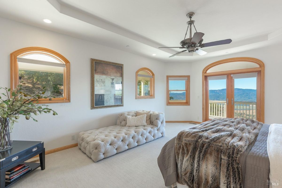 Bright bedroom with a cushioned bench and arched windows providing outdoor views.