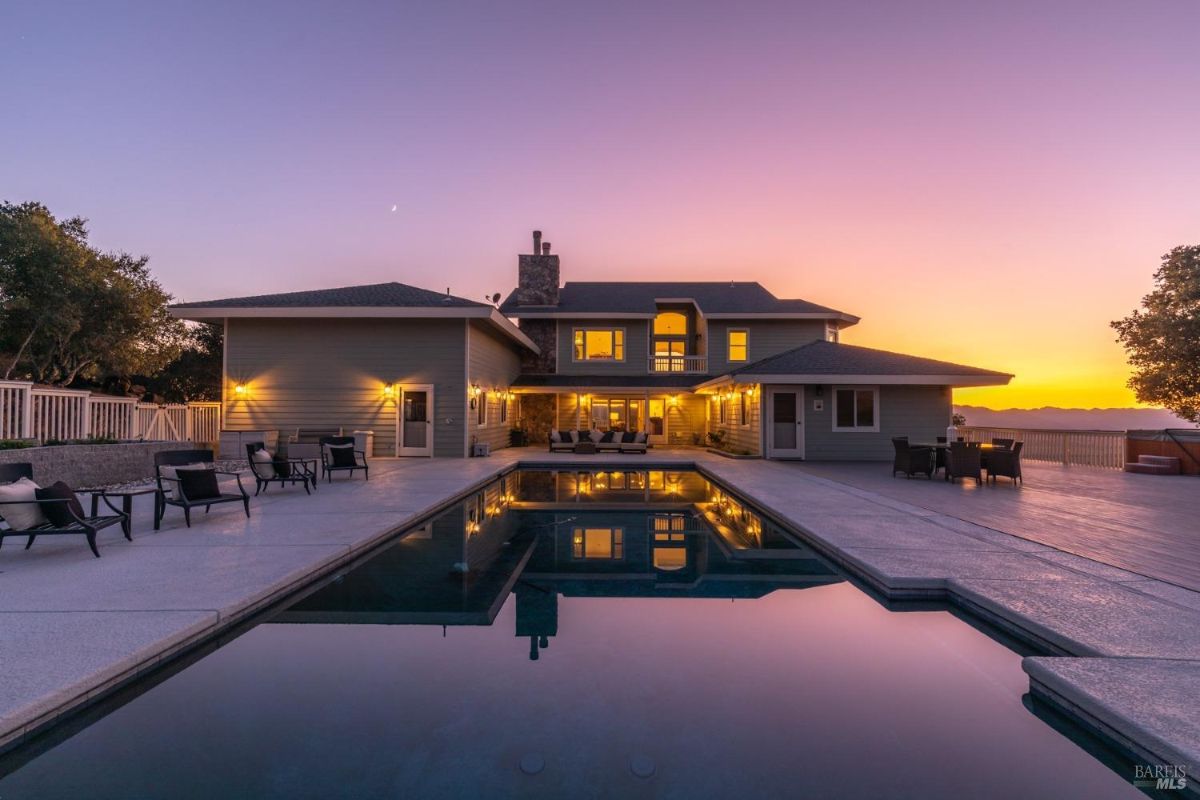 Backyard features a swimming pool surrounded by a patio and outdoor seating areas.