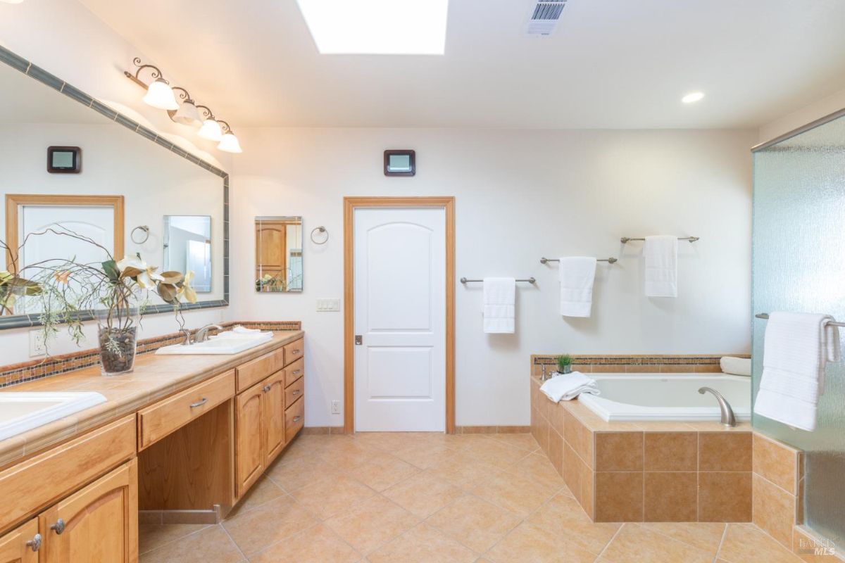 Spacious bathroom featuring dual sinks, a bathtub, and wooden cabinetry.