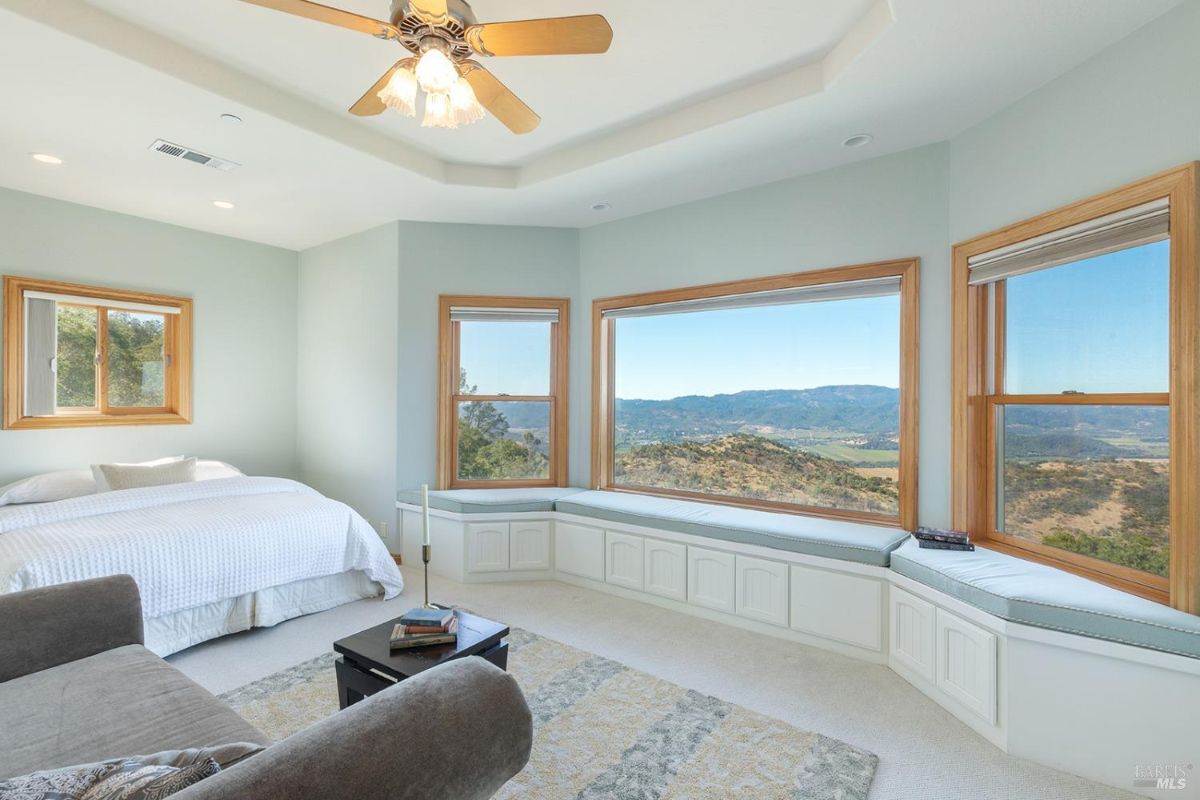 Spacious bedroom with wrap-around bench seating under bay windows and a simple modern design.