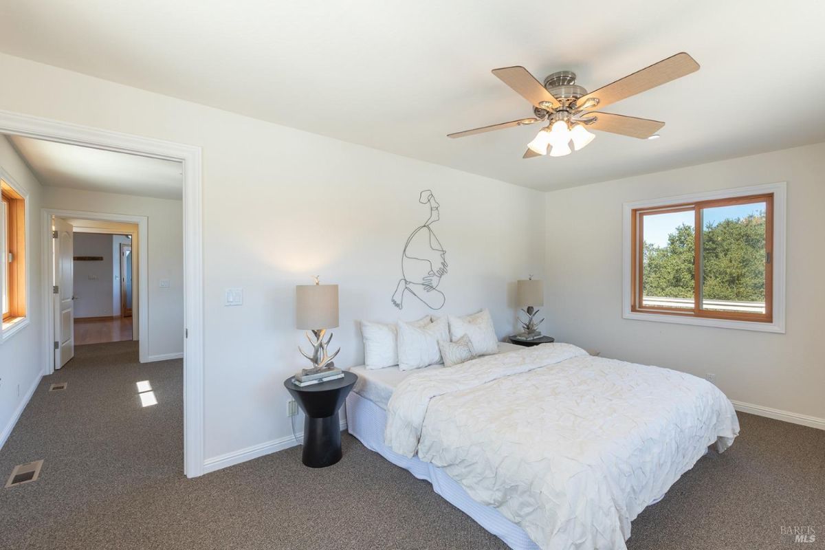 Smaller bedroom with a minimalist design, featuring a wall-mounted art piece and ceiling fan.