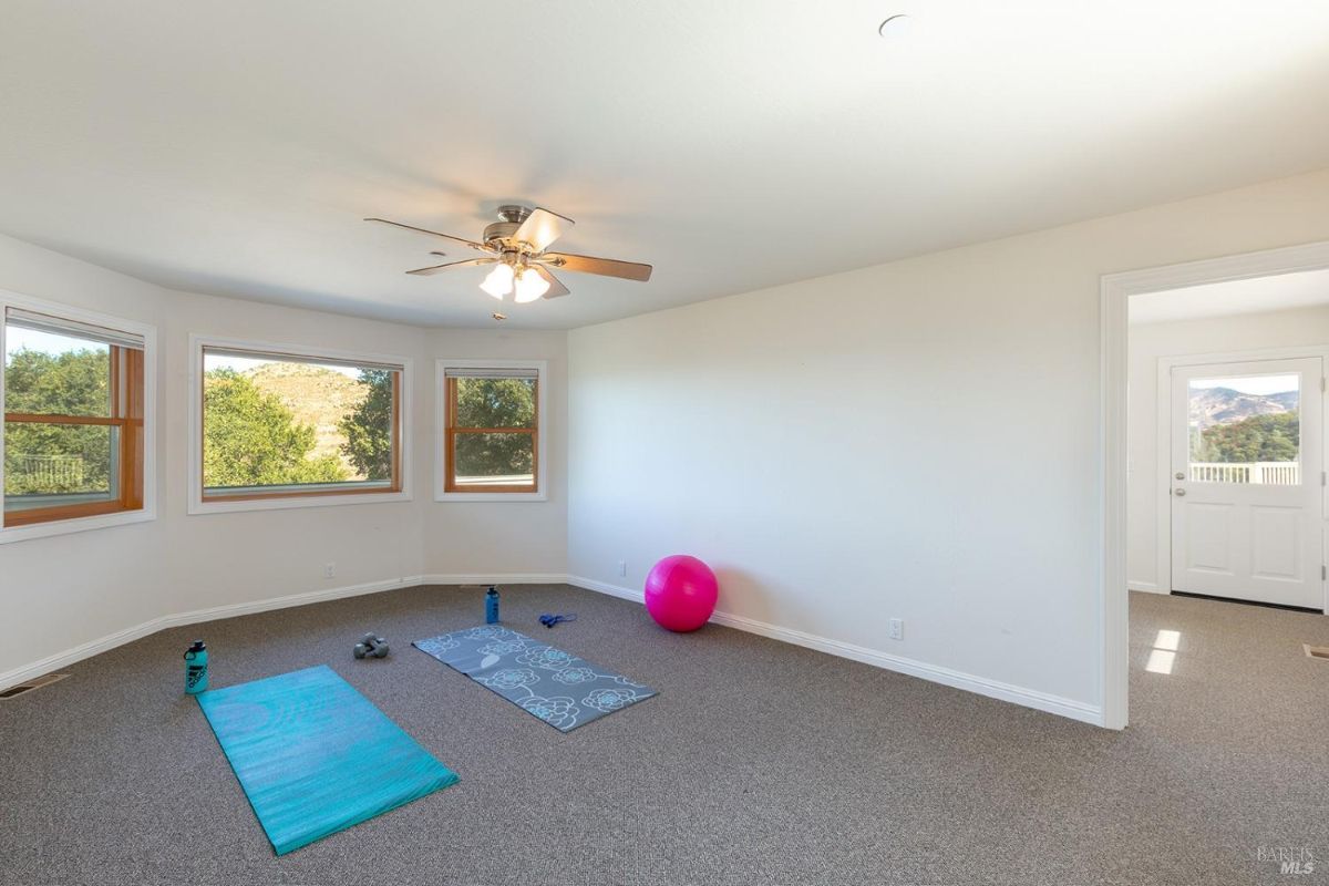 Exercise equipment with large windows overlooking greenery.