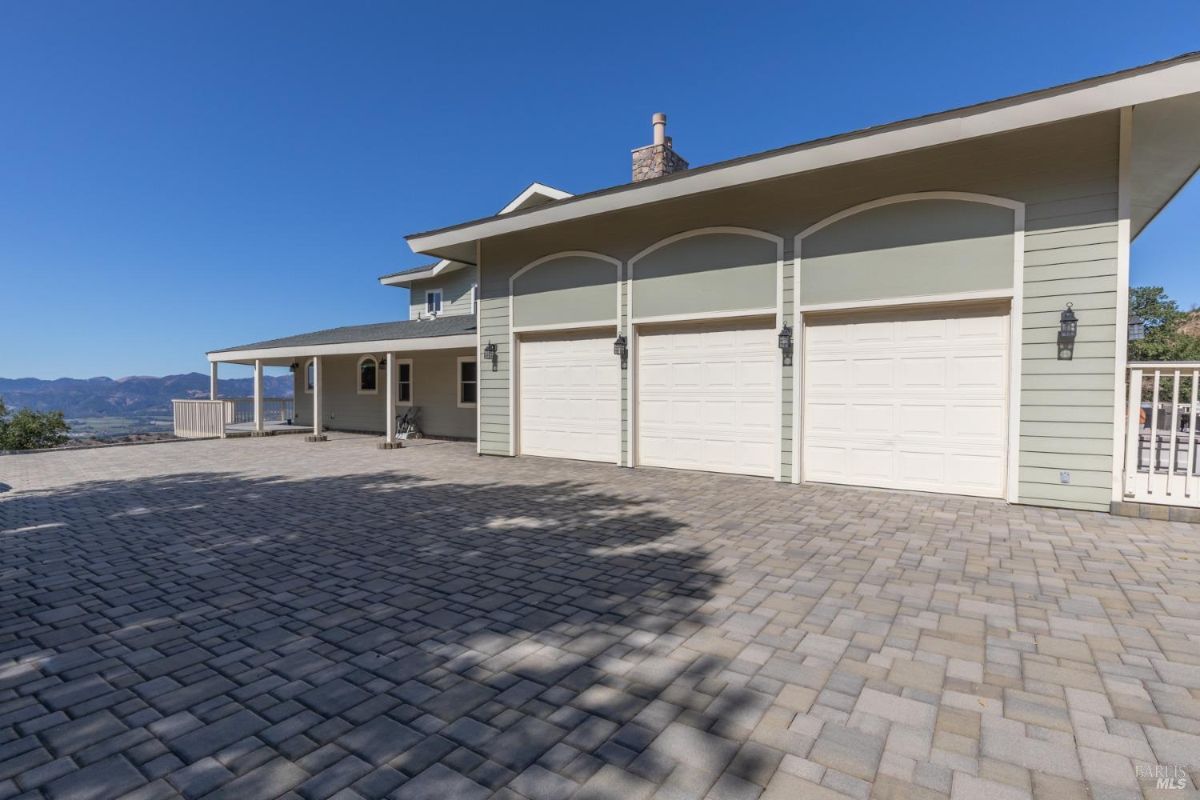 Three-car garage with a paved driveway and mountain backdrop.