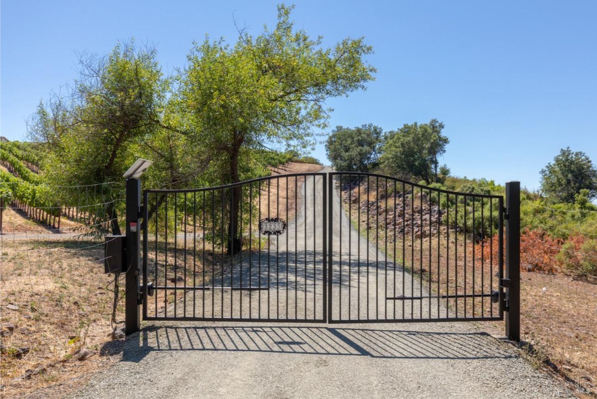 Gated entrance to a private property with a gravel driveway.