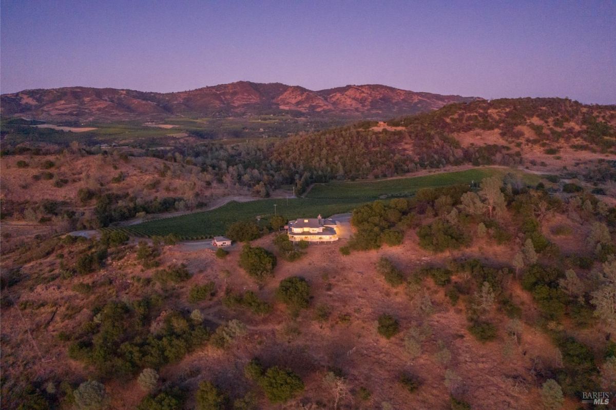 Dusk view of the house with surrounding hills and vineyards.