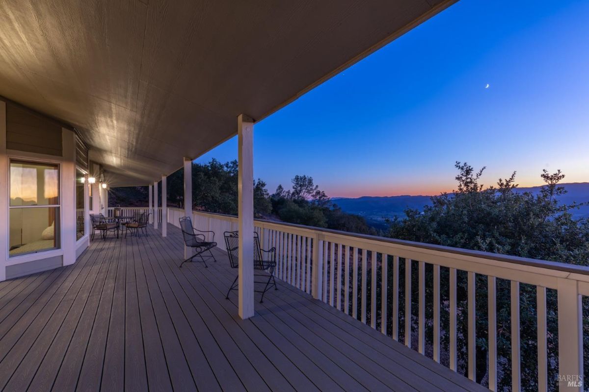 Outdoor wraparound porch with seating and mountain views during twilight.