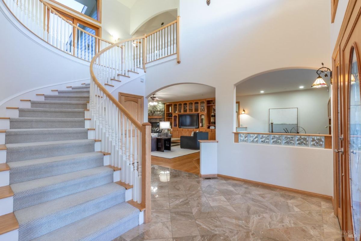 Interior view of a staircase with carpeted steps and an open living area featuring built-in wooden cabinets.