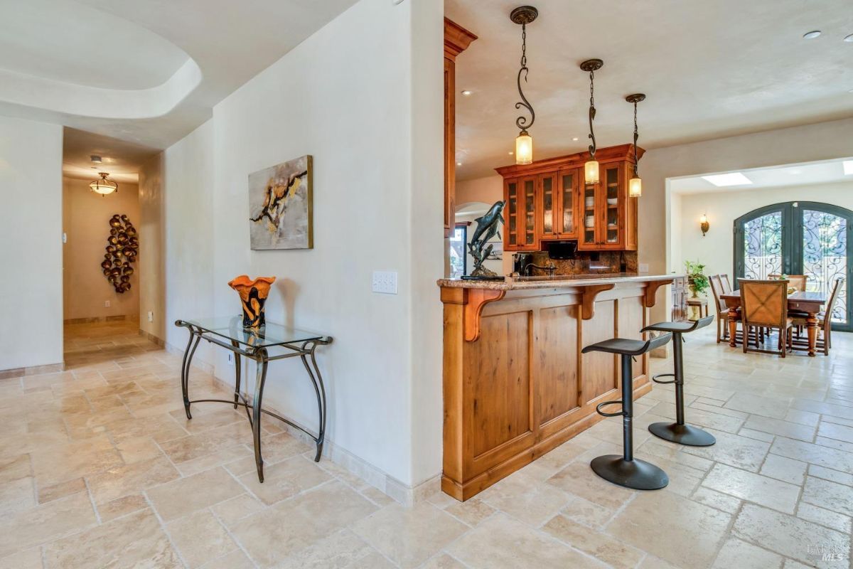 Kitchen with a breakfast bar, a dining table, and a hallway leading to another room.