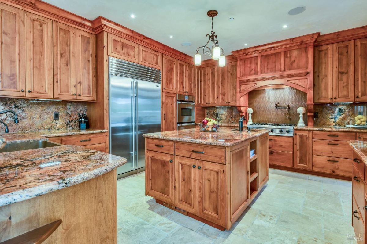 The kitchen has wooden cabinets, granite countertops, and a large island with a sink and stovetop.