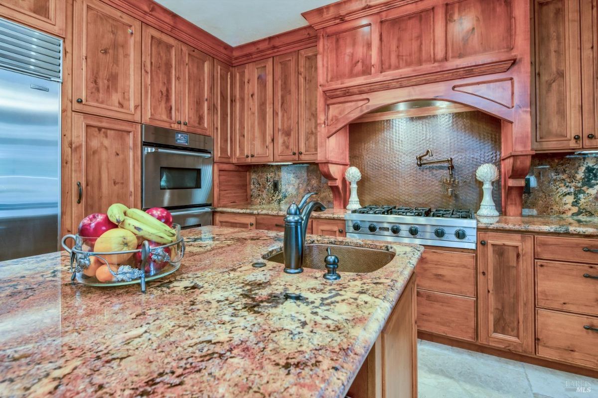 The kitchen countertop features a granite surface with a bowl of fruit.