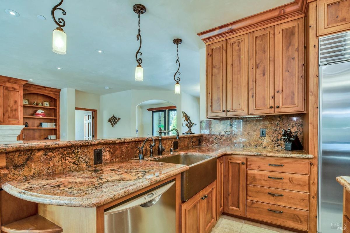 The kitchen has a large granite countertop, a double sink, and wooden cabinets.