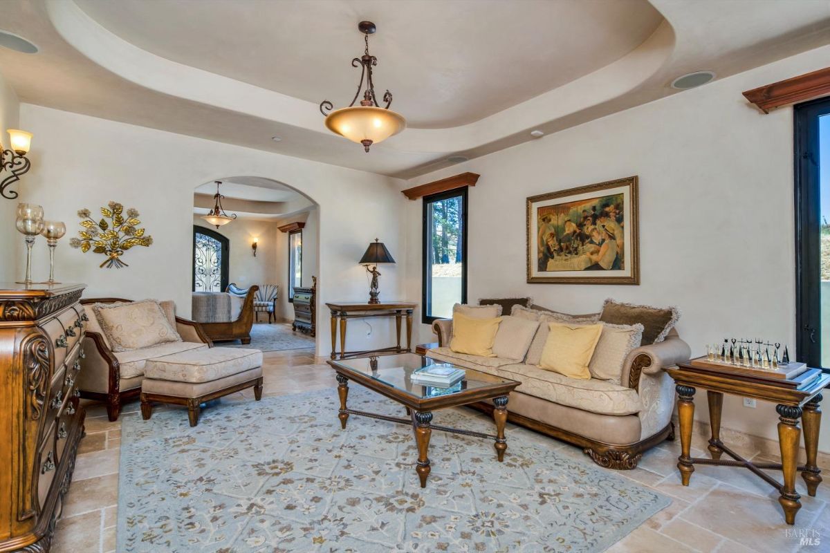 Traditional sitting room featuring ornate furniture, a large rug, and an arched entryway.