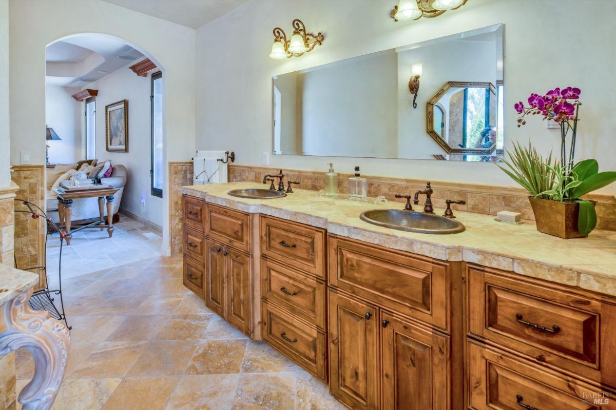 The bathroom features a double sink vanity with wooden cabinets and a large mirror.