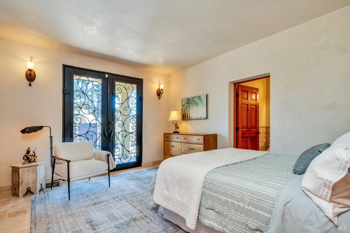 The bedroom features a bed with a white comforter, a dresser, and a chair with a side table.