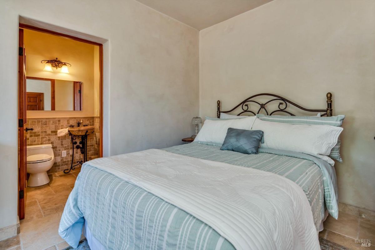 The bedroom features a bed with a patterned comforter and a view of an attached bathroom.