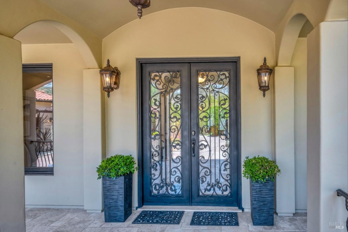 Front entrance of the house featuring double wrought-iron doors and decorative wall-mounted lanterns.