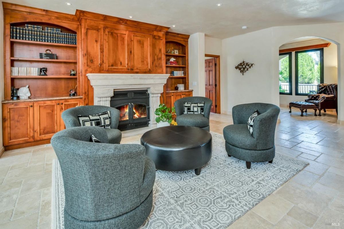 Library or study room with built-in wood bookshelves, a fireplace, and cozy seating.