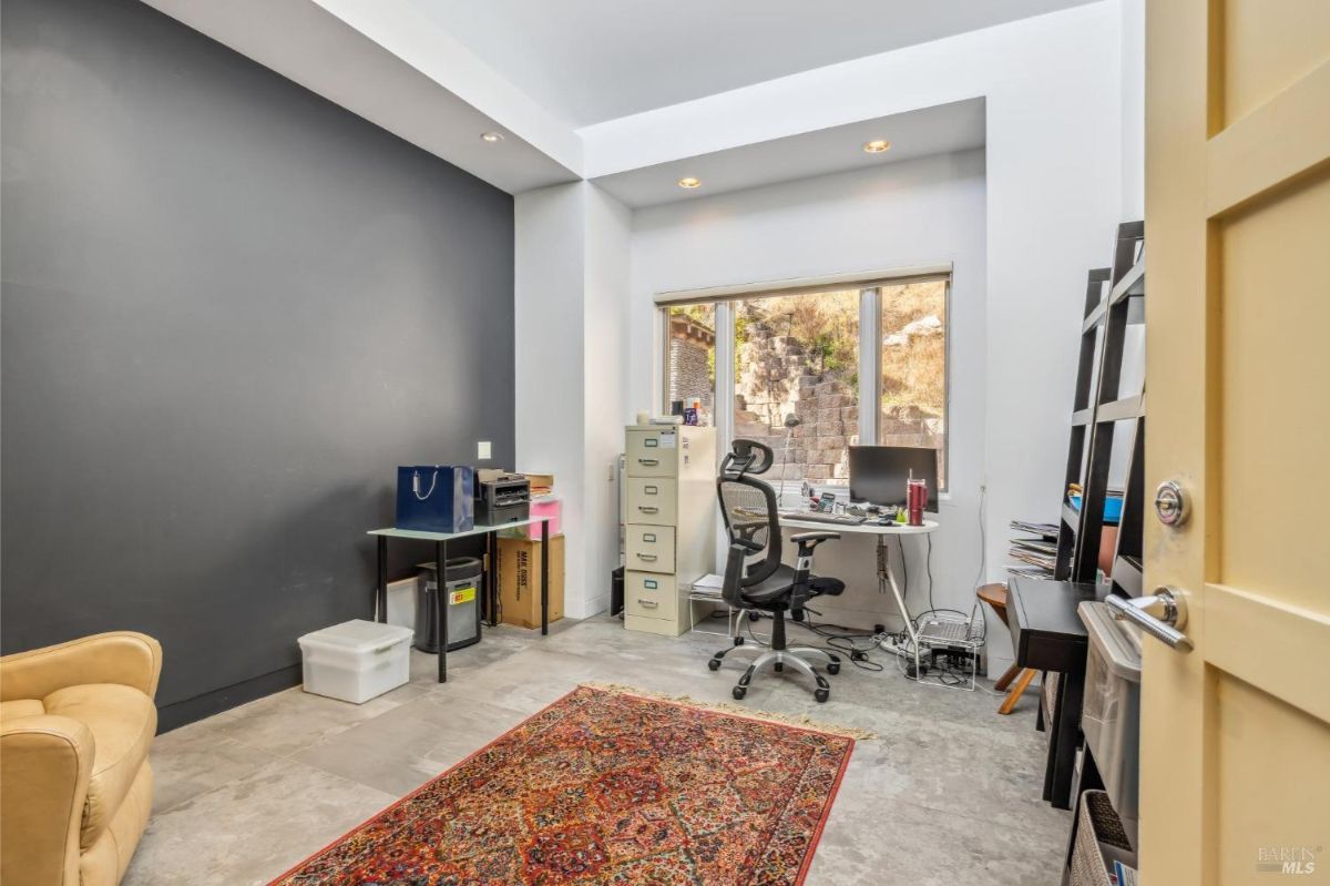 Workroom with a desk, shelving, and a large window facing the outdoors.