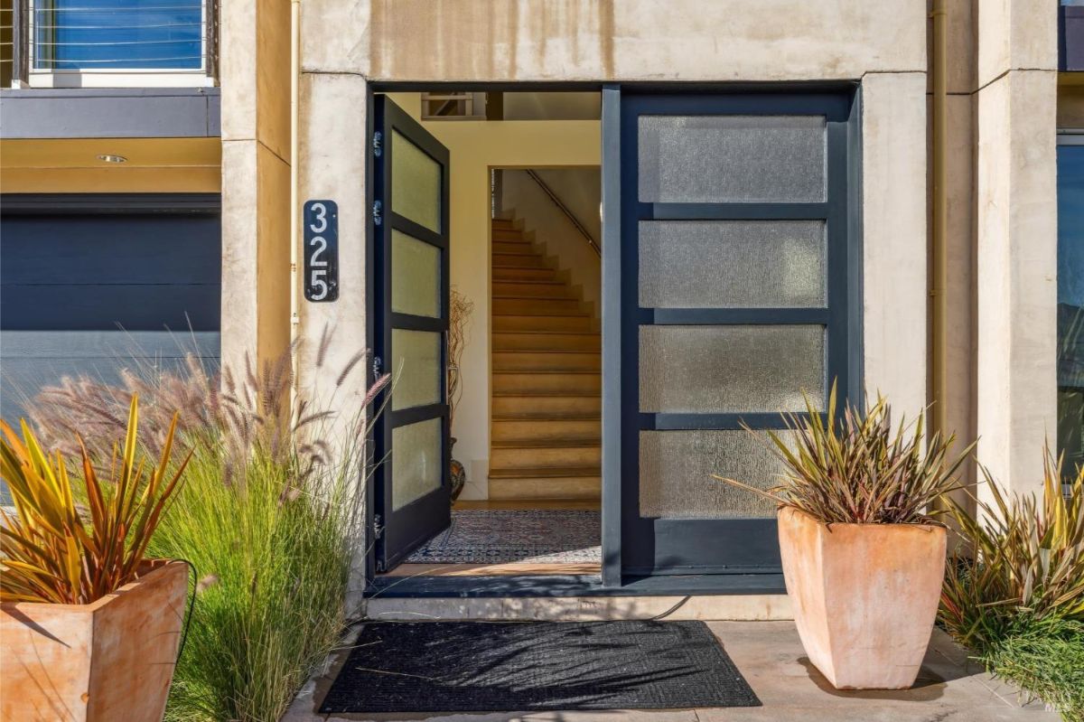 Entrance with double doors surrounded by frosted glass panels and planters.