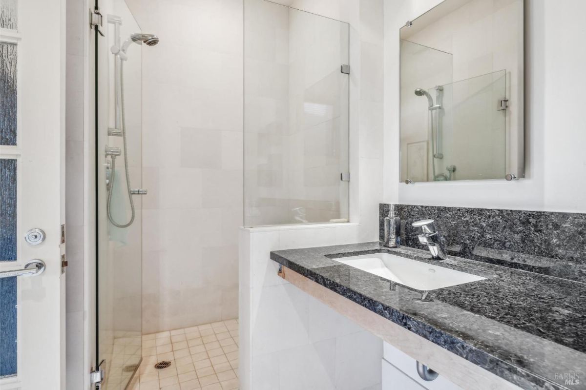 Bathroom featuring a granite countertop and a glass-enclosed shower.