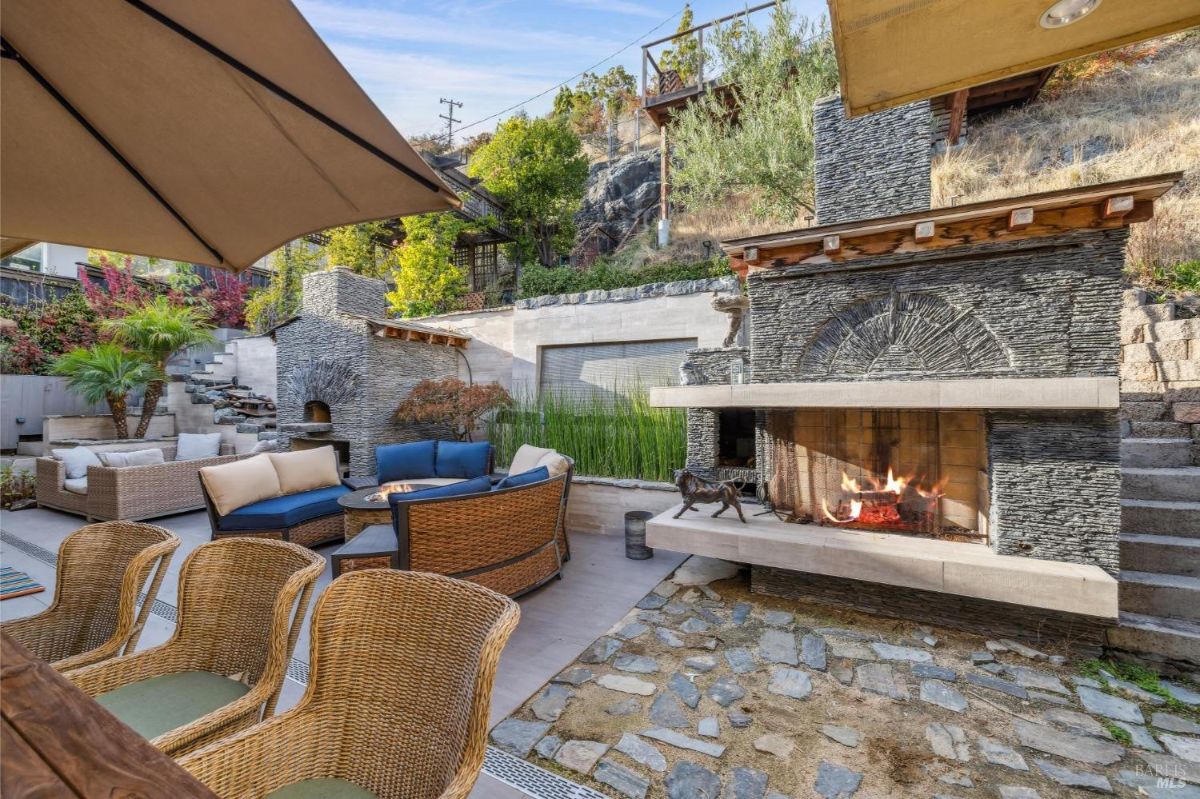 Outdoor fireplace and lounge area with wicker furniture and a tiered garden.