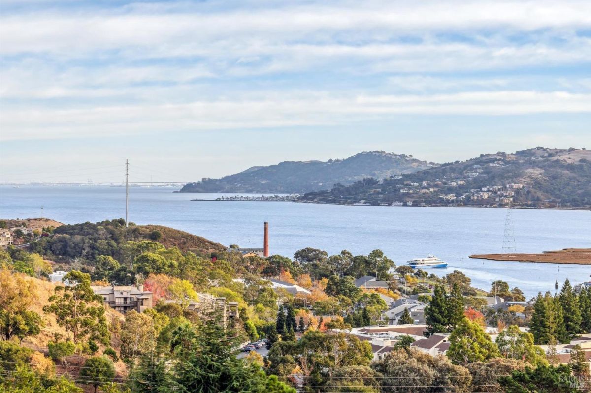 Landscape view showing a waterfront area with houses and hills.