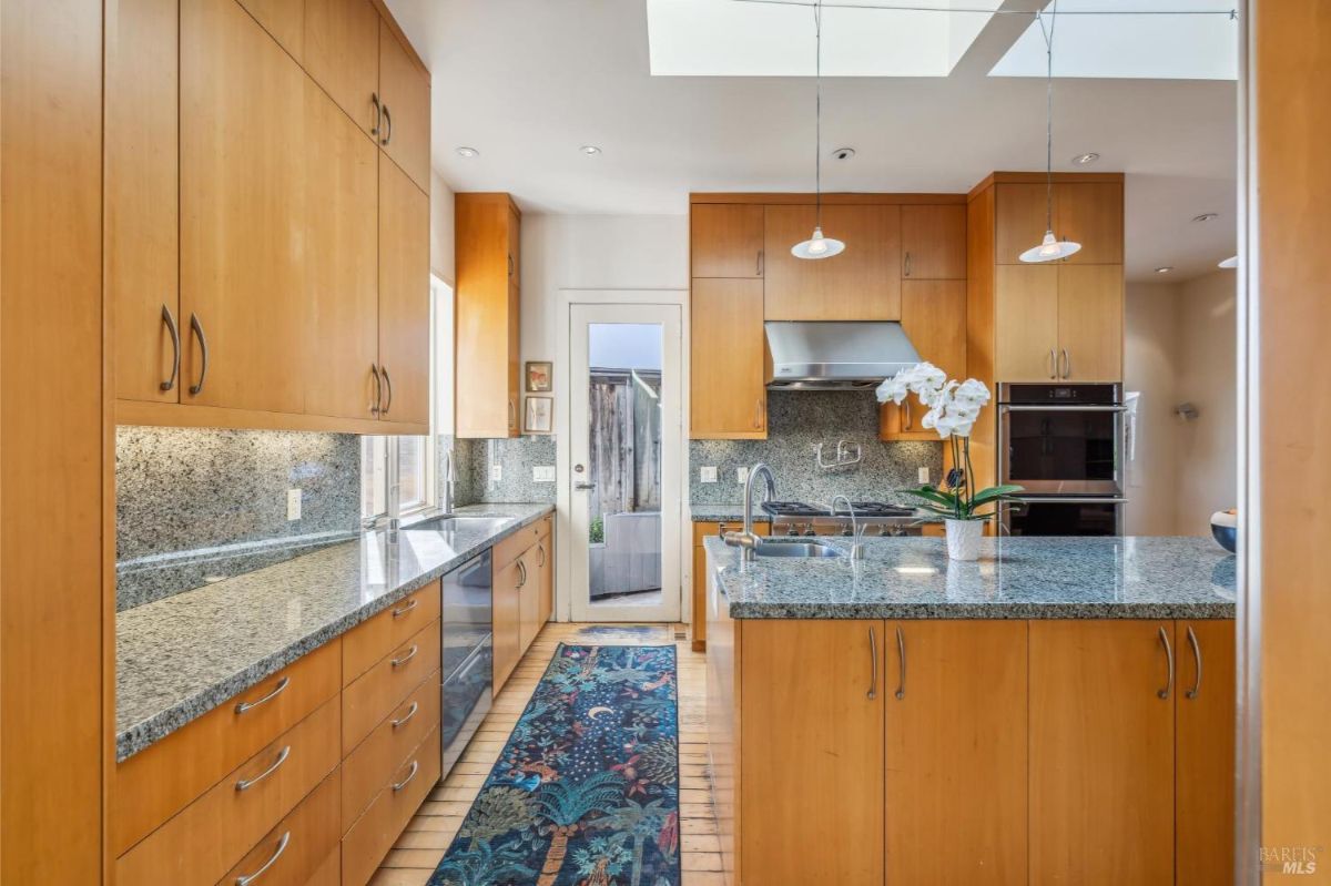 Galley-style kitchen with ample natural light, a skylight, and access to an outdoor area.