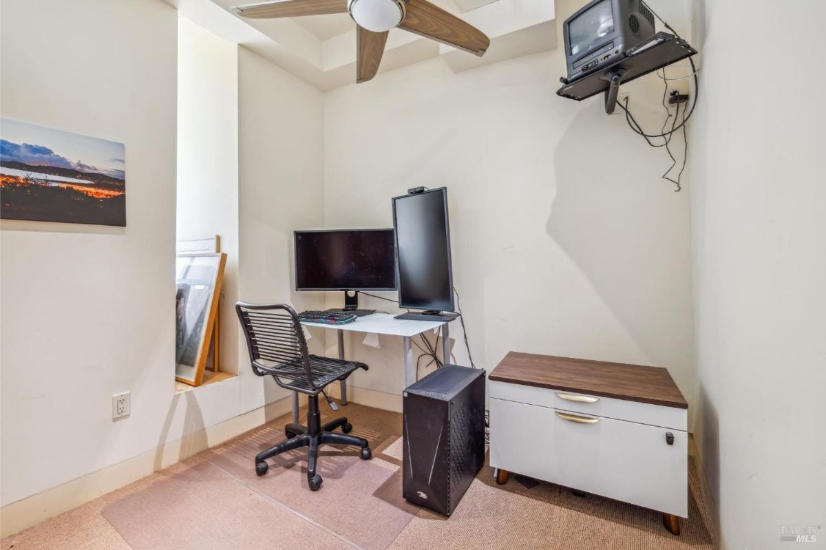 Home office with a computer desk, chair, and mounted television.