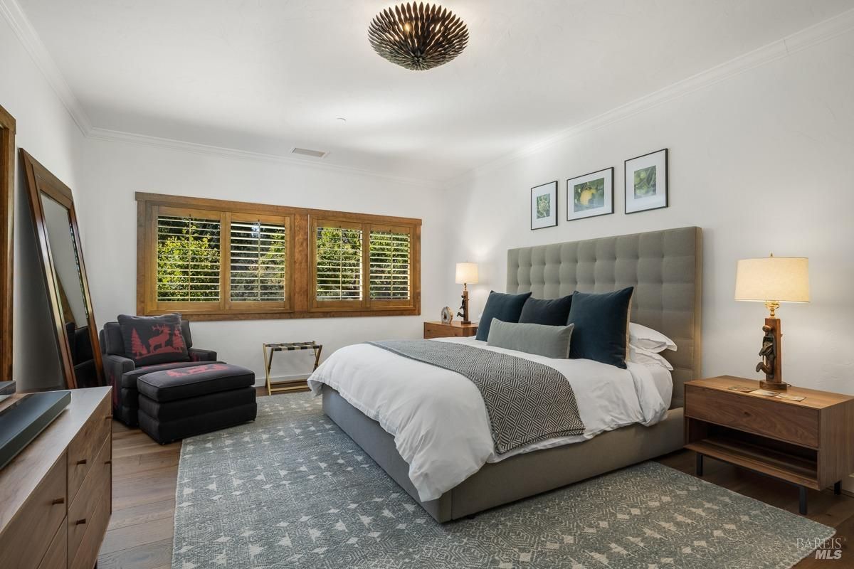 A bedroom that combines modern comfort with rustic elements, such as a wood-paneled wall and sliding glass doors leading to a garden. The warm tones and built-in shelves enhance the cozy atmosphere.