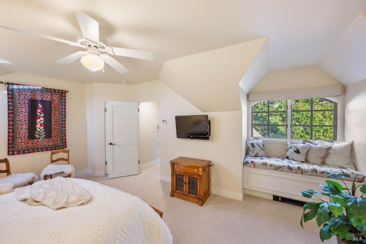 Bedroom featuring a window seat, quilted bedding, and a wall-mounted TV.