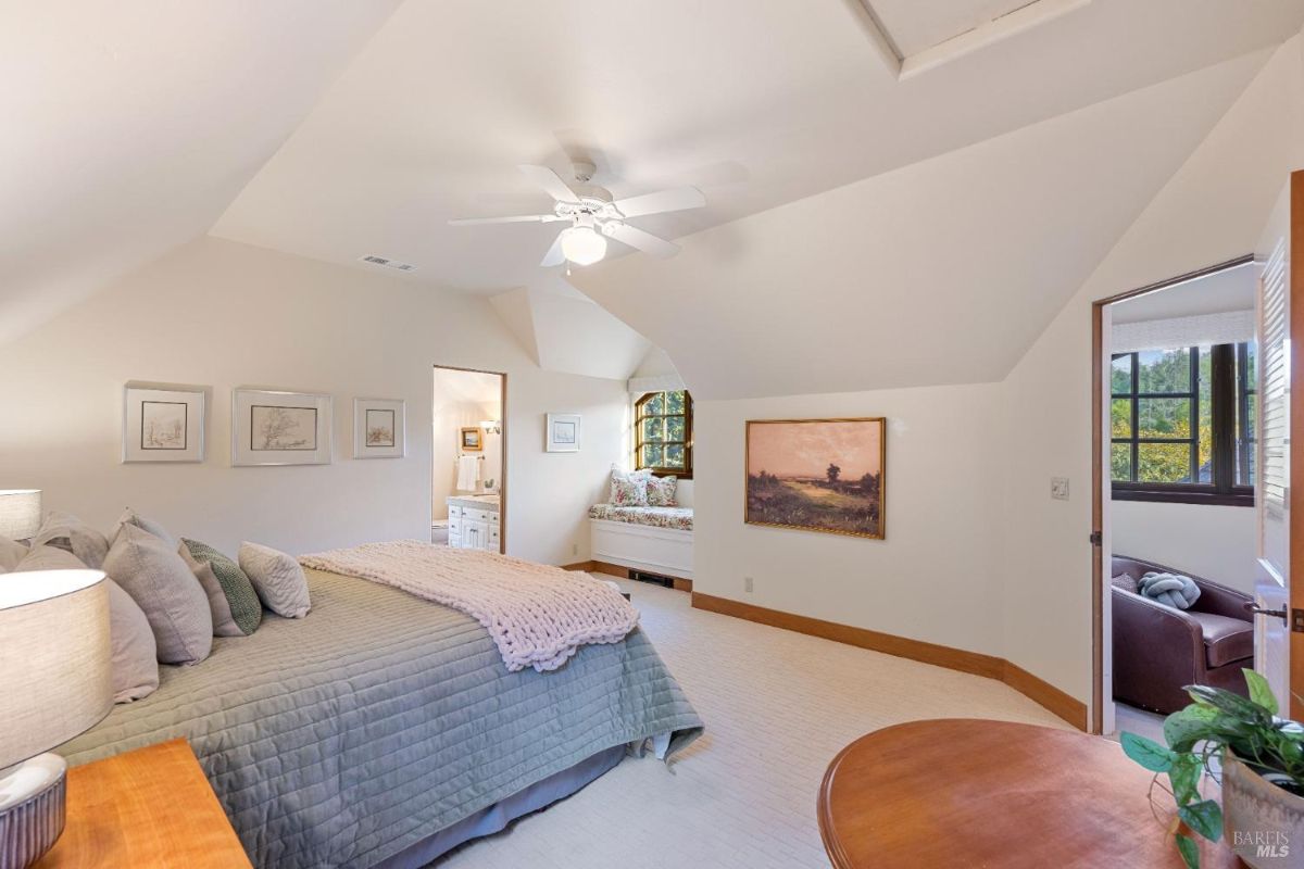 Bedroom with angled ceilings, a window seat, and soft, neutral decor.