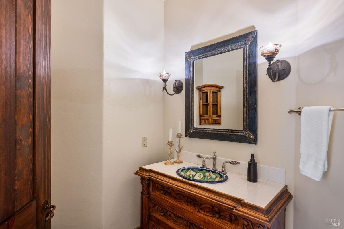 Bathroom with a carved wooden vanity, decorative sink, and ornate framed mirror.