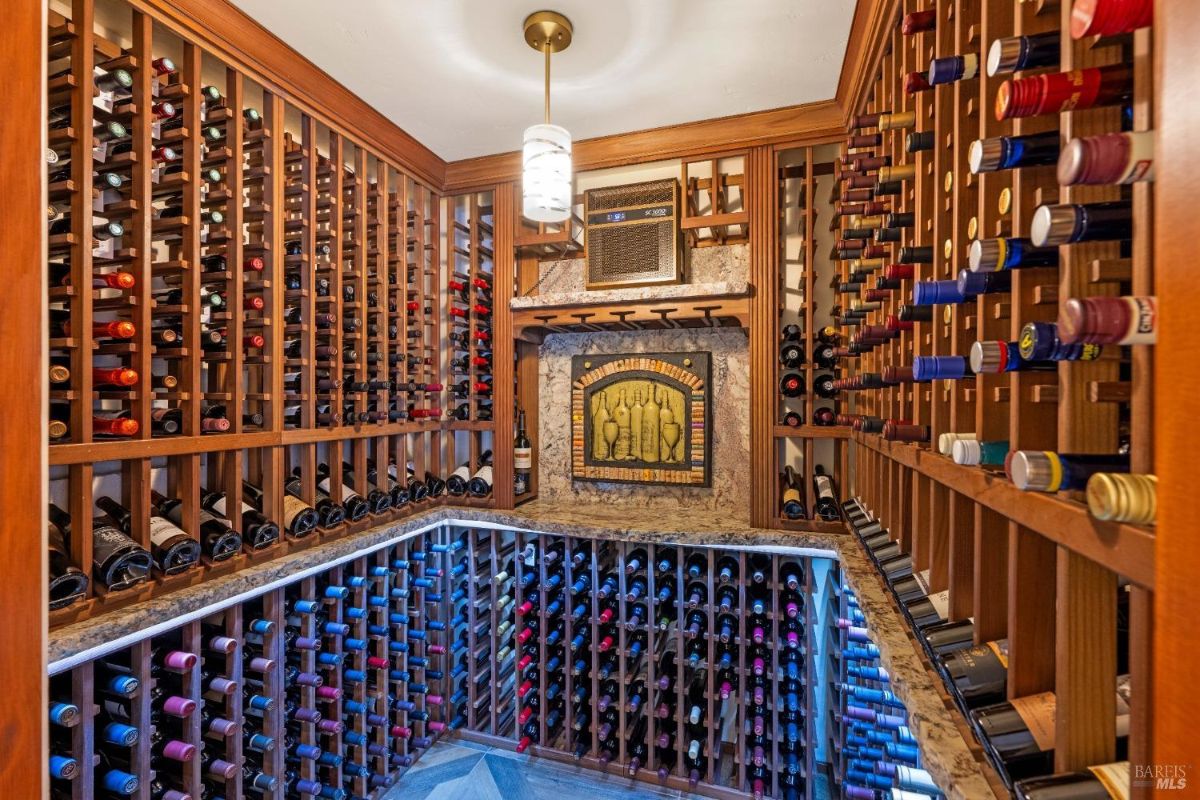 Wine cellar with custom wood racks, a cooling unit, and a decorative wine-themed tile piece.