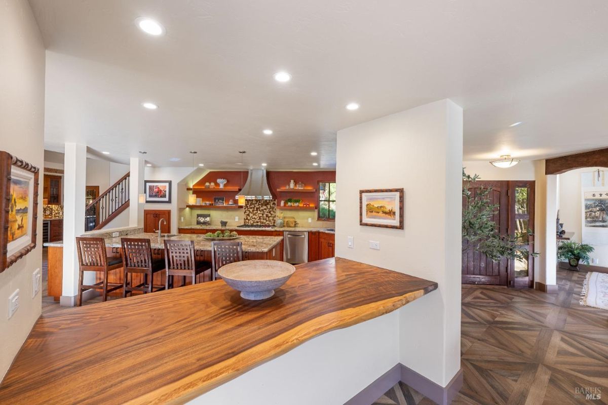 Kitchen with a live-edge wooden countertop, granite island, and bar seating.