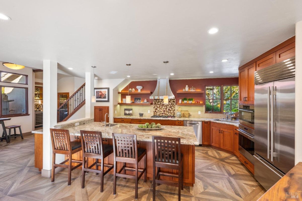 Kitchen with granite countertops, a large island, stainless steel appliances, and open shelving.