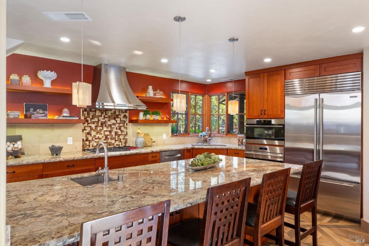 Kitchen featuring a mosaic tile backsplash, a range hood, and natural light from multiple windows.